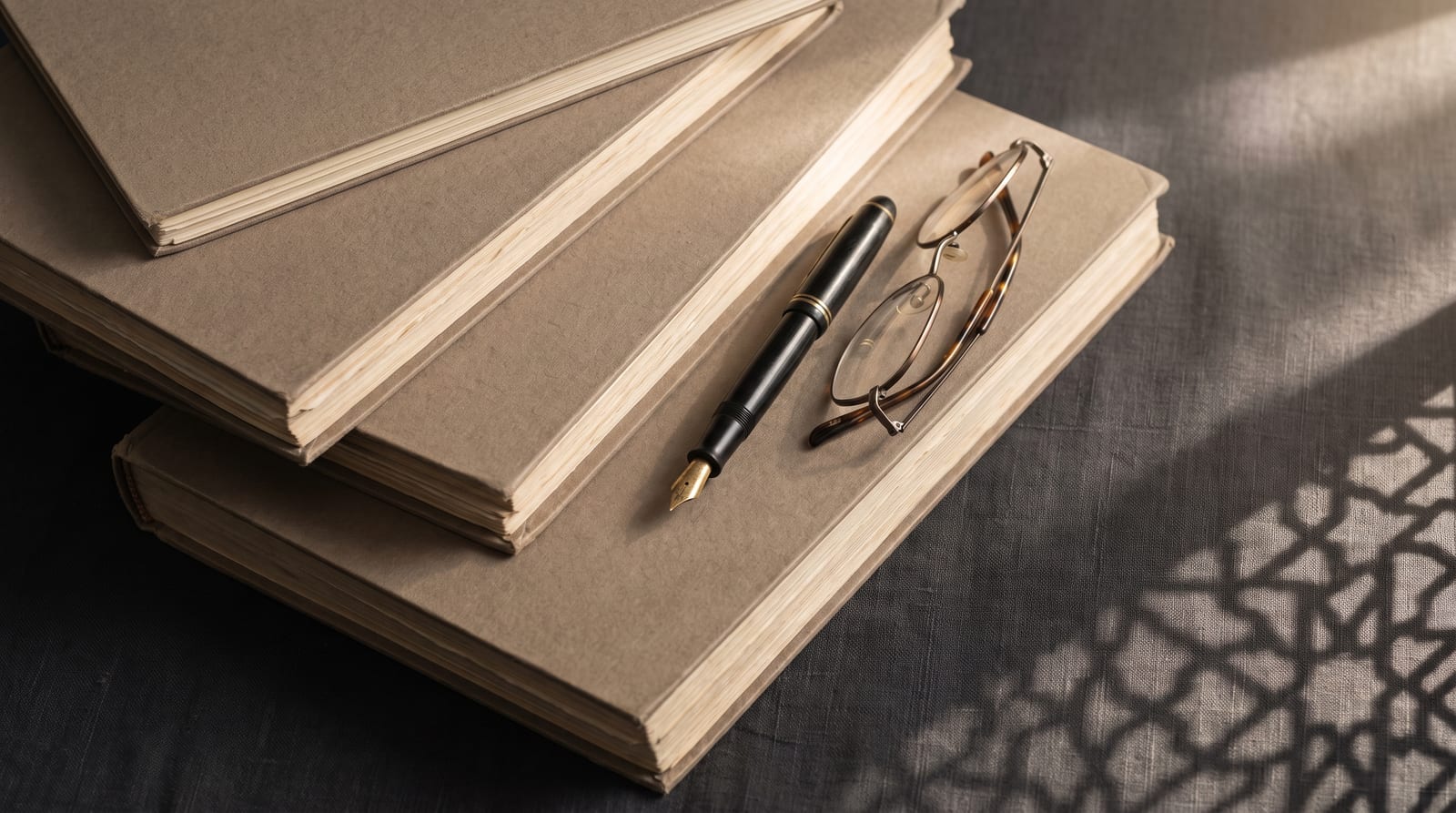 Trois dossiers juridiques d'épaisseurs différentes empilés sur un bureau, avec un stylo plume et des lunettes